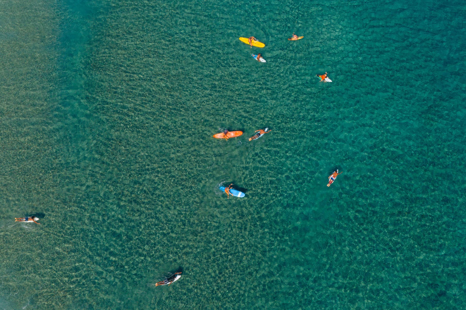 Surfers paddling out over clear green water